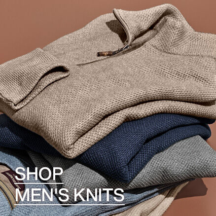 Stack of men's knit sweaters in neutral and navy tones, featuring a textured quarter-zip sweater on top. Text reads &ldquo;Shop Men's Knits.&rdquo;